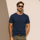 Man wearing a navy blue t-shirt and sunglasses against a beige wall
